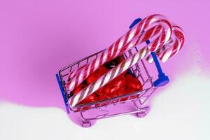 een supermarkt trolley geladen met snoepjes en Kerstmis karamel wandelstokken foto