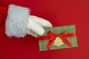 santa's handen zijn Holding een geschenk voor kerstmis. rood achtergrond foto