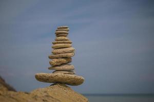 balancerende piramide van stenen op een grote steen aan de kust foto