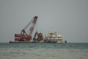 drijvende kraan en vrachtschip werken in de zee foto