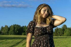 mooi meisje in jurk Aan de achtergrond van een groen veld- in zomer foto