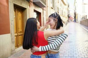 gelukkig Aziatisch Dames knuffelen Aan straat foto