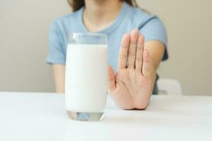 allergie Aziatisch jong vrouw, meisje hand- in ontkennen, Nee of Duwen uit naar vermijden voor drinken melk Bij huis, ongelukkig en slecht maag pijn. lactose onverdraagzaamheid en zuivel voedsel, Gezondheid probleem, buik lijden concept. foto