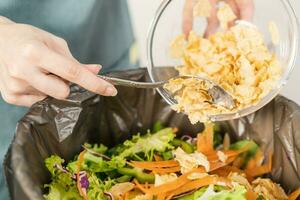 compost de keuken afval, recyclen, biologisch maaltijd Aziatisch jong huishouden vrouw schrapen, het werpen voedsel restjes in de afval, uitschot bak van groente. milieuvriendelijk aansprakelijk, ecologie. foto