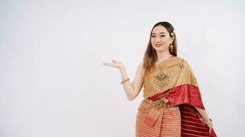 Aziatisch vrouw vervelend typisch, traditioneel Thais jurk met identiteit Thais cultuur presenteren iets over- geïsoleerd wit achtergrond foto