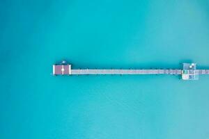 top visie van toerist kanoën door houten pier in turkoois zee Aan zomer Bij tropisch eiland foto