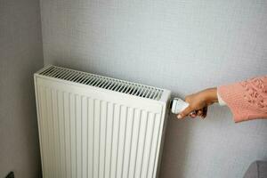 Dames hand- aanpassen de temperatuur van een radiator foto