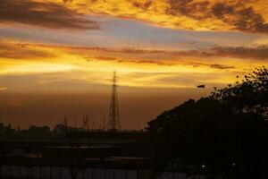 zonsondergang over- de stad, silhouet van een hoog Spanning transmissie toren foto