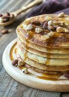 stack van pannekoeken met esdoorn- siroop en noten foto