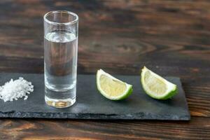glas van tequila met limoen wiggen foto