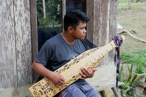 kuaro Kalimantan timur, Indonesië 21 juni 2023. een Mens spelen een traditioneel Kalimantan dayak musical instrument foto