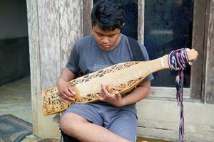 kuaro Kalimantan timur, Indonesië 21 juni 2023. een Mens spelen een traditioneel Kalimantan dayak musical instrument foto