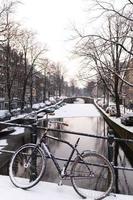 fiets en gracht in amsterdam in de sneeuw foto