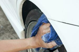 hand- van de auto wassen met blauw kleding Aan de deksel van de olie tank wit auto. foto