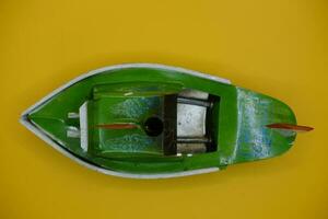 boot otok ok, een traditioneel speelgoed- van Indonesië. een knal knal boot speelgoed- dat toepassingen stoom- stroom. speelgoed- schip geïsoleerd geel achtergrond. foto