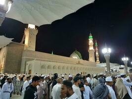 medina, saudi Arabië, mei 2023 - mooi nacht tijd visie van masjid al nabawi, medina. bezoekers, binnenplaatsen buiten de moskee, mooi lichten en elektronisch paraplu's kan ook worden gezien. foto