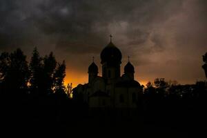 de silhouet van de koepels van een orthodox christen kerk in Roemenië tegen de achtergrond van de rood lucht. geloof of religie concept foto