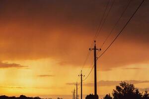 hoog voltage macht lijnen Bij zonsondergang. elektriciteit distributie station. elektriciteit pylonen Aan de achtergrond van de lucht foto