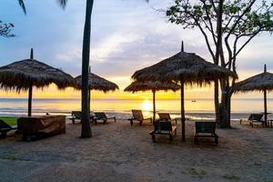 paraplu en stoel op tropisch strand met zonsopgang foto