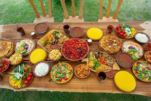 eigengemaakt Roemeense voedsel met gegrild vlees, polenta en groenten schotel Aan camping. romantisch traditioneel Moldavisch voedsel buiten Aan de hout tafel. foto