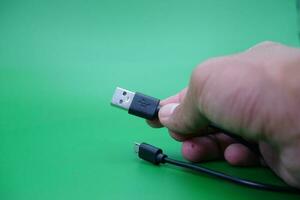 hand- Holding USB type een naar USB micro b kabel geïsoleerd Aan groen achtergrond. foto