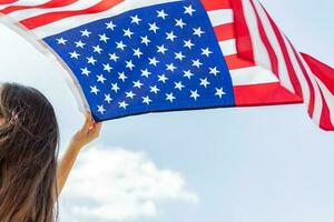 jong Kaukasisch vrouw Holding Amerikaans vlag Aan blauw lucht achtergrond. foto