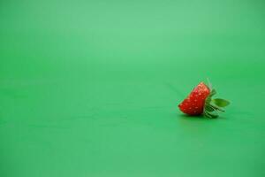een rood aardbei geïsoleerd Aan een groen achtergrond. gebeten aardbeien. foto