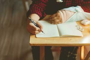 handen van mannetje studenten beschrijven groeten Hallo brieven naar klasgenoten, zijn Rechtsaf arm was zetten Aan een spalk terwijl zittend Bij huis afwezig van school- bericht schrijven essay studie en leerling vriend concept foto