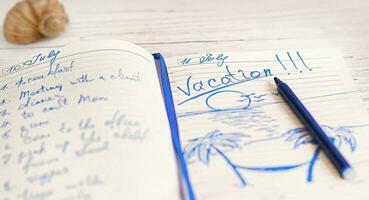 kladblok dagboek Aan de tafel met de planning van de dag en reizen naar de zee Aan vakantie. foto