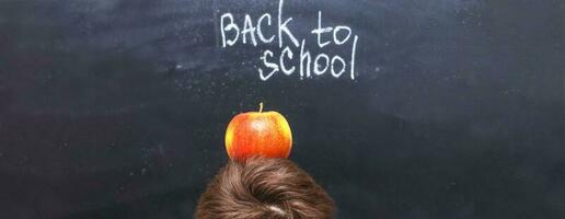 een appel Aan een kind hoofd in de buurt schoolbord. terug naar school- concept achtergrond foto