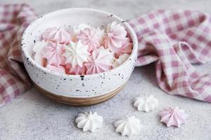kleine witte en roze schuimgebakjes in de keramische kom foto