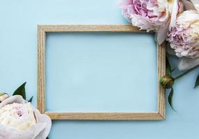 houten frame omgeven door mooie roze pioenrozen op een blauwe achtergrond foto