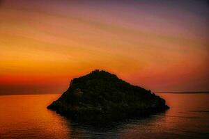 de eiland van bergeggi gedurende een zonsondergang met de helder kleuren van een mooi zomer avond in 2022 foto