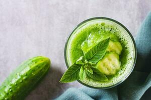 dichtbij omhoog van verfrissend komkommer en munt smoothie in een glas Aan de tafel top visie foto