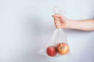 hand- Holding een beschikbaar transparant zak met appels foto