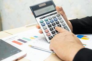 Aziatische accountant werken en analyseren van financiële rapporten projectboekhouding met grafiek, grafiek en rekenmachine in moderne kantoren foto