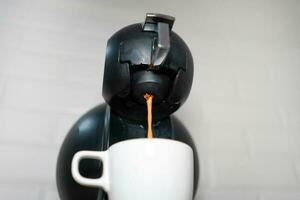 koffie maken met uitdrukken. koffiezetapparaat. gieten koffie naar klein beker. automatisch koffie maker. foto