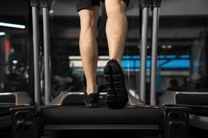 close-up van mannelijke benen die op de loopband in de sportschool lopen