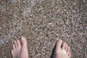 voeten op het zand in de zee in de zomer foto