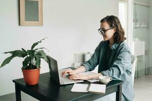 jong vrouw werken Aan laptop in modern kantoor. leerling meisje aan het studeren of freelancen van huis. thuiswerken, bedrijf, en levensstijl concept. technologie, productiviteit, opleiding, en afgelegen werk foto