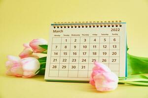 kalender en bloemen Aan geel achtergrond foto