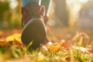 vrouw laarzen met een esdoorn- herfst bladeren achtergrond foto