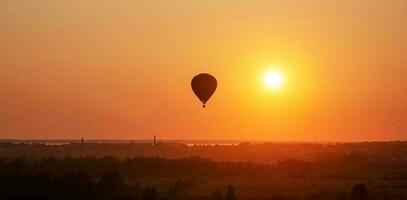 kleurrijk lucht ballon is vliegend in vrij vlucht over- de veld. vogelperspectief visie. veelkleurig ballon in de lucht Bij zonsondergang foto