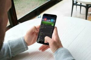 Mens weddenschappen leven Aan een Amerikaans voetbal bij elkaar passen door een mobiel telefoon app. de concept van online sport- wedden. een modern app voor mobiel platformen foto