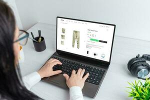boodschappen doen voor kleren online. vrouw bladert lading broek Aan een ecommerce website foto