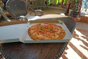 grote pizza in een kartonnen doos op een houten tafel foto