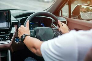 Mens bestuurder het rijden een auto Aan de weg, hand- controlerend stuurinrichting wiel in elektrisch modern auto. reis, reis en veiligheid vervoer concepten foto