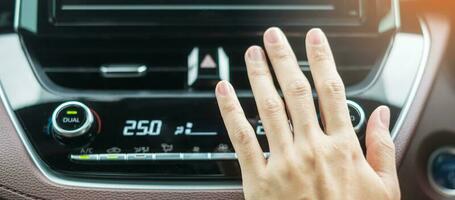 vrouwenhand die de lucht controleert die tijdens het autorijden op de weg stroomt, het koelsysteem van de airconditioner in de auto. aanpassen, temperatuur en transportconcept foto