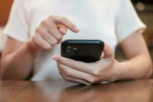 casual zakenvrouw die smartphone vasthoudt en gebruikt voor sms-berichten, jonge vrouw die touchscreen mobiele telefoon typt in café of modern kantoor. lifestyle, technologie, sociale media en netwerkconcept foto