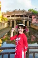 vrouw reiziger vervelend oa dai Vietnamees jurk bezienswaardigheden bekijken Bij Japans gedekt brug in Hoi een dorp, Vietnam. mijlpaal en populair voor toerist attracties. Vietnam en zuidoosten Azië reizen concept foto